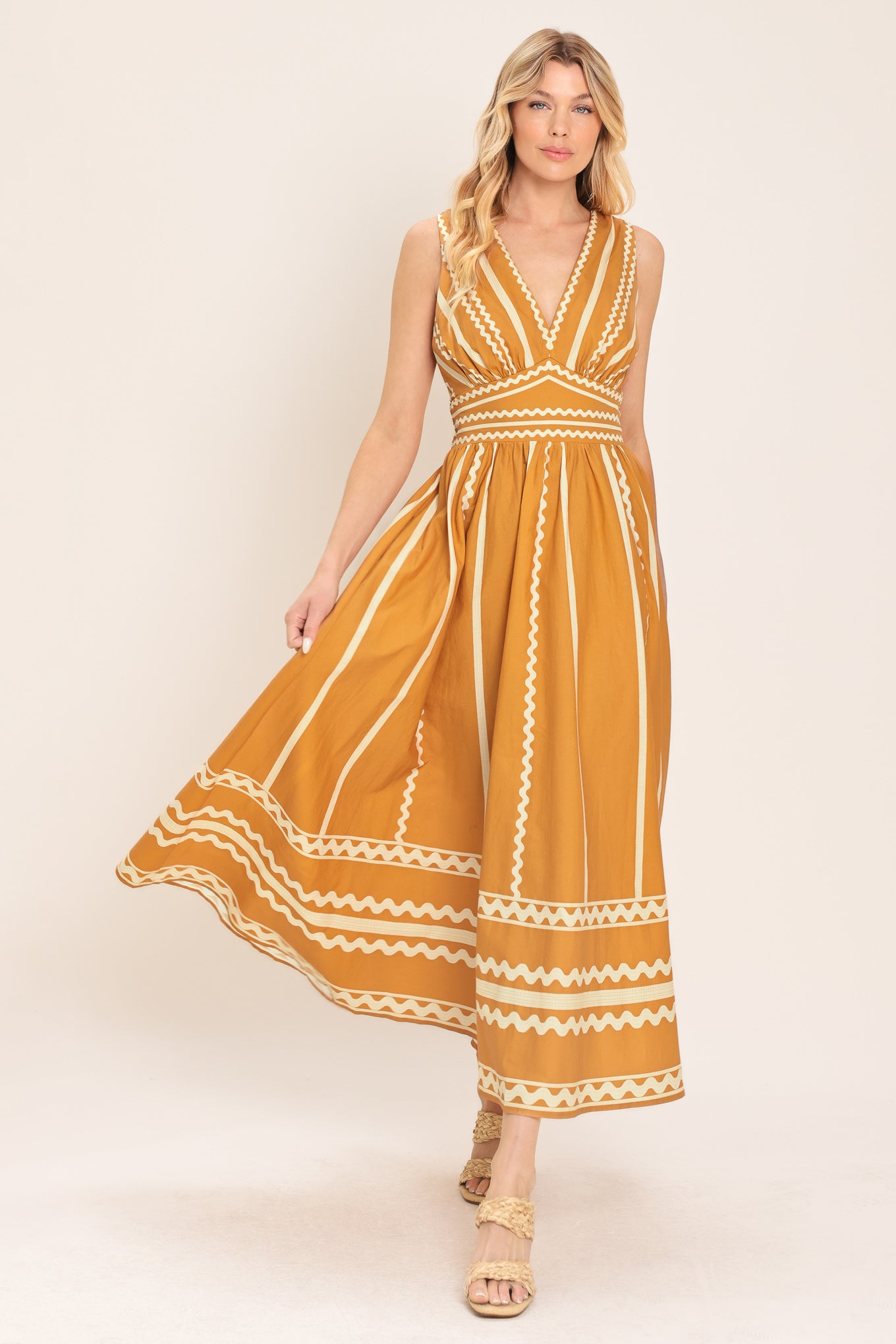 Woman wearing a mustard yellow midi dress with white patterns featuring V neckline, sleeveless, waist yoke, full skirt and smocked back waistband | Flying Tomato