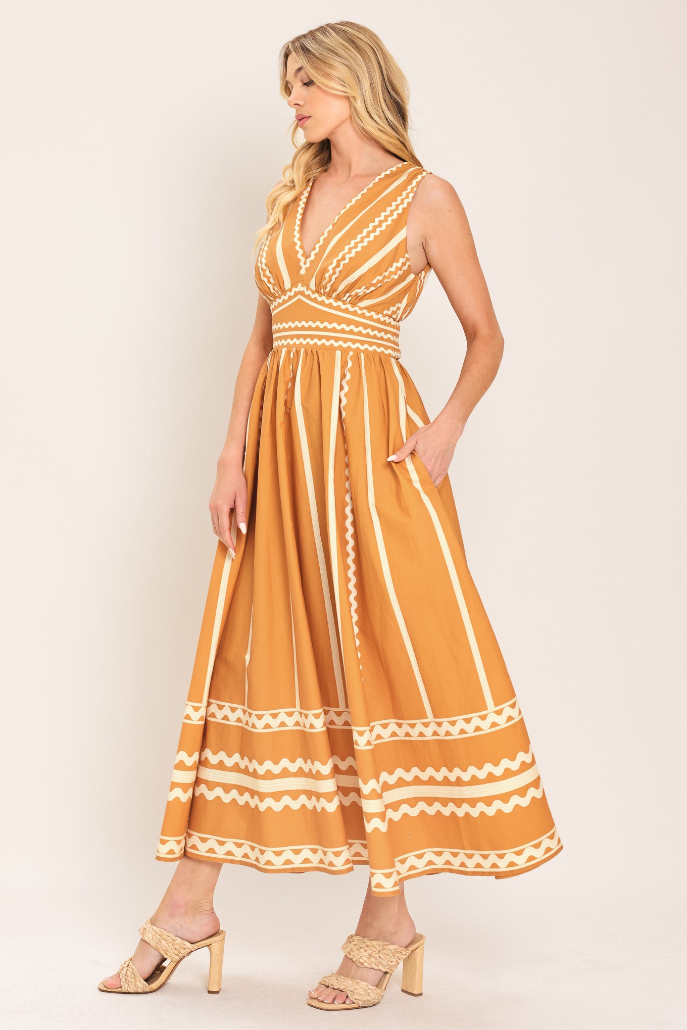 Woman wearing a mustard yellow midi dress with white patterns featuring V neckline, sleeveless, waist yoke, full skirt and smocked back waistband | Flying Tomato
