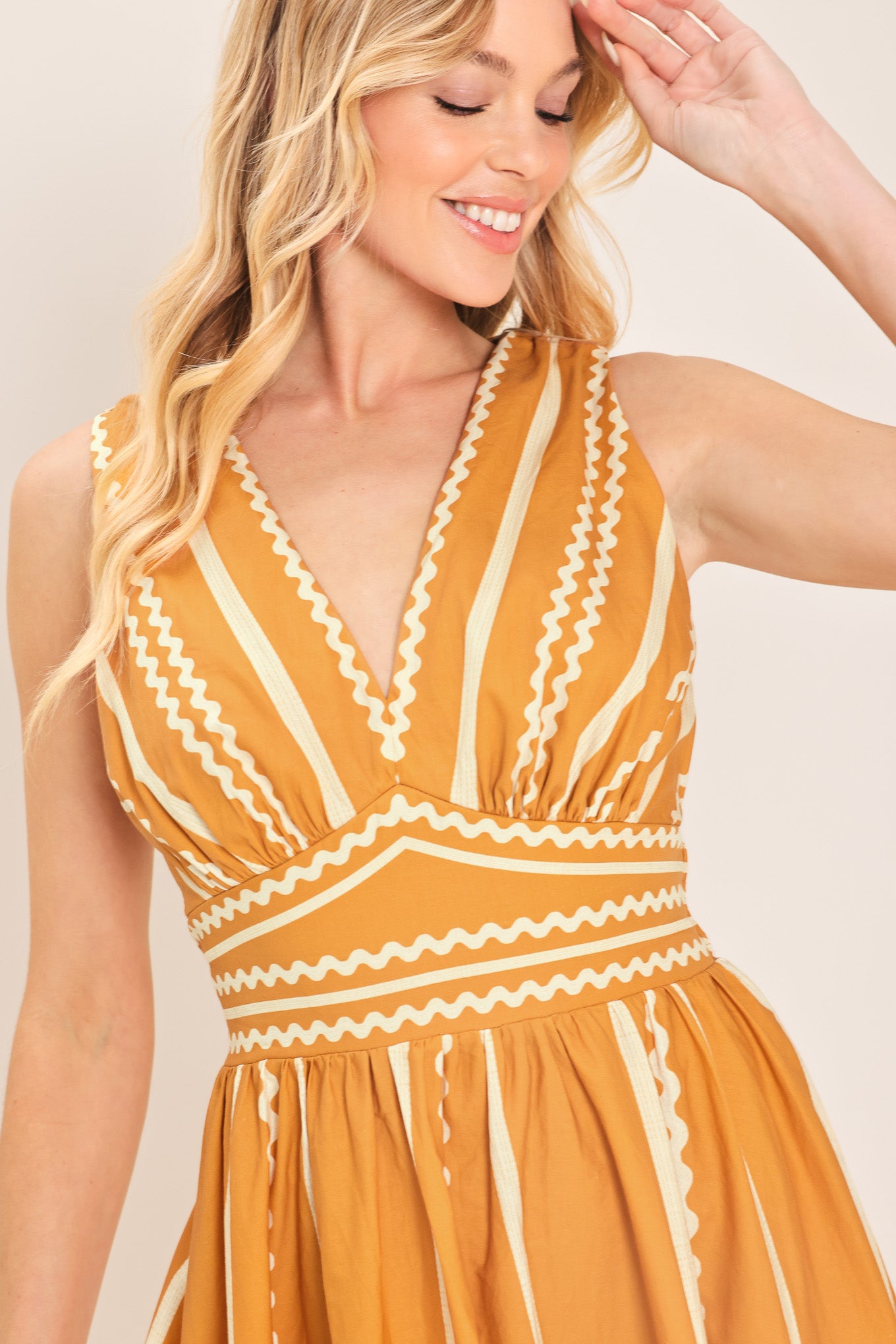 Woman wearing a mustard yellow midi dress with white patterns featuring V neckline, sleeveless, waist yoke, full skirt and smocked back waistband | Flying Tomato