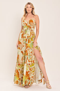 Woman wearing a colorful tropical floral maxi dress featuring cami top, wide smocked waist, slit tier skirt and bare back with cross straps | Flying Tomato