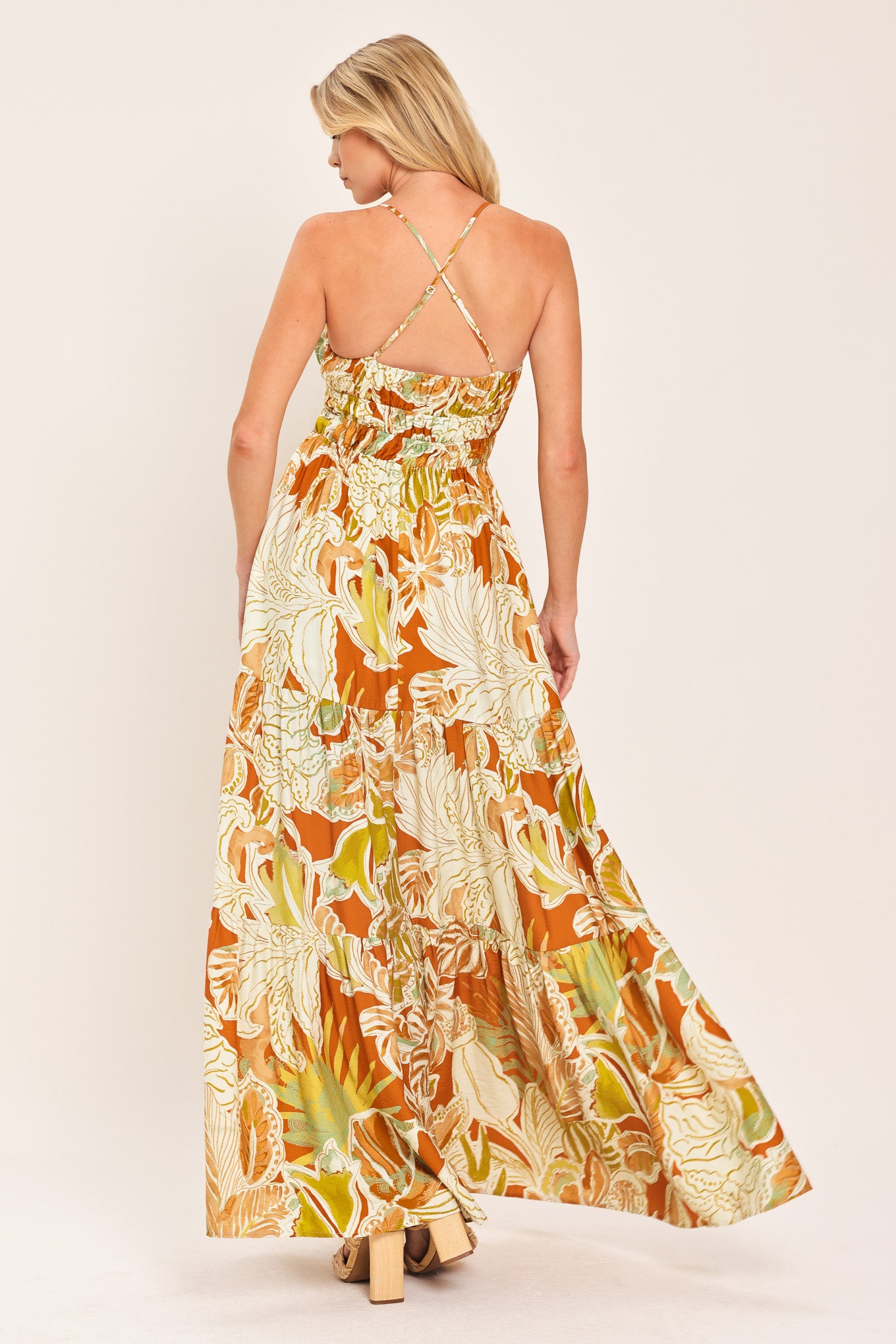 Woman wearing a colorful tropical floral maxi dress featuring cami top, wide smocked waist, slit tier skirt and bare back with cross straps | Flying Tomato