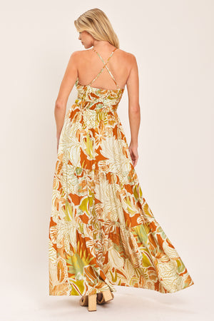 Woman wearing a colorful tropical floral maxi dress featuring cami top, wide smocked waist, slit tier skirt and bare back with cross straps | Flying Tomato