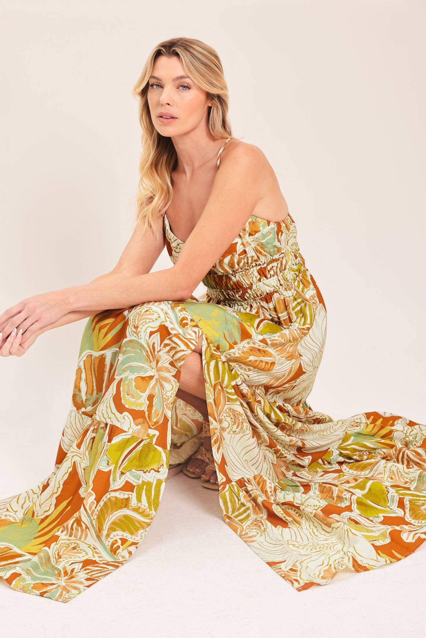 Woman wearing a colorful tropical floral maxi dress featuring cami top, wide smocked waist, slit tier skirt and bare back with cross straps | Flying Tomato