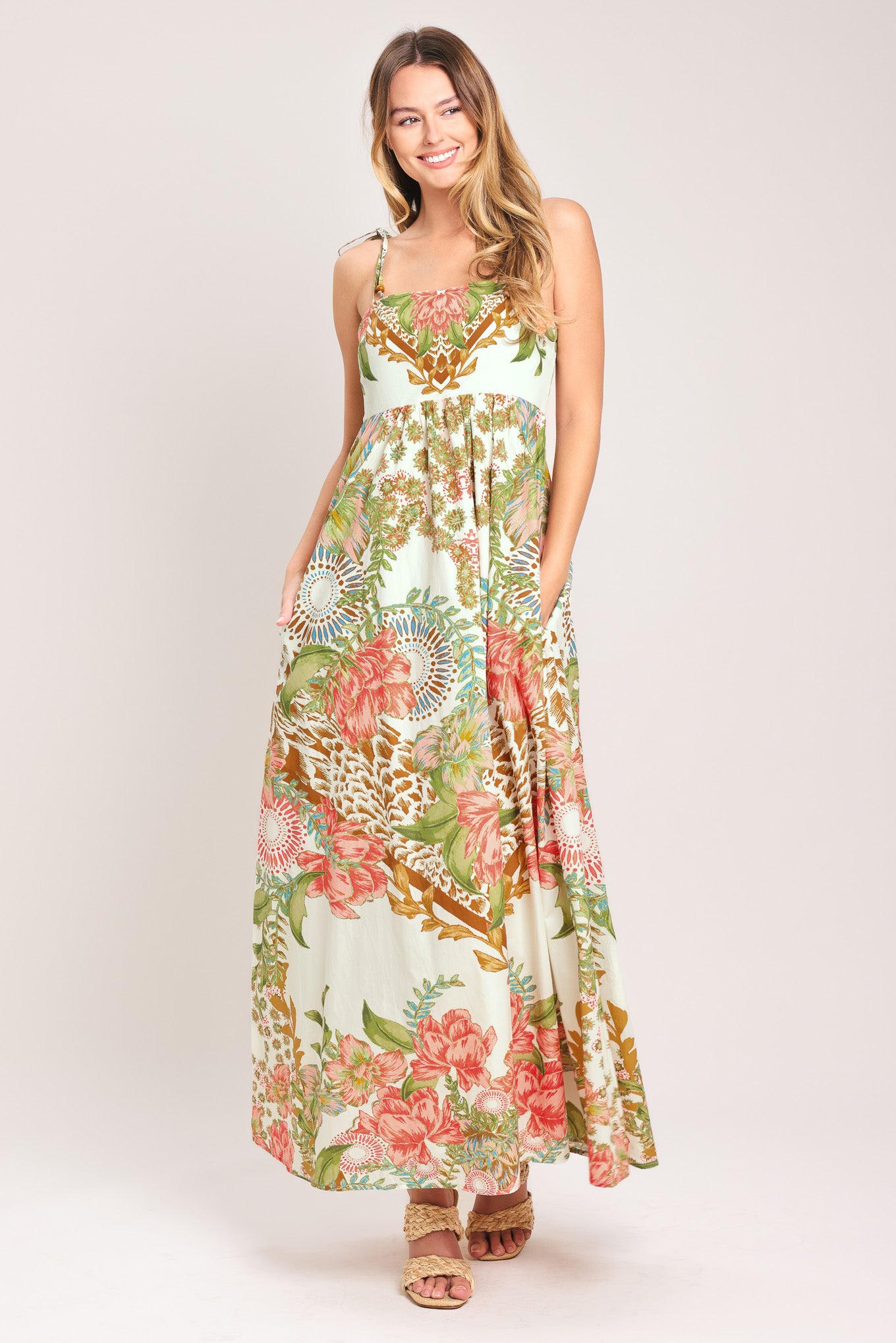 Woman wearing a floral ankle dress featuring straight neckline with shoulder tie, full skirt and smocked back bodice | Flying Tomato