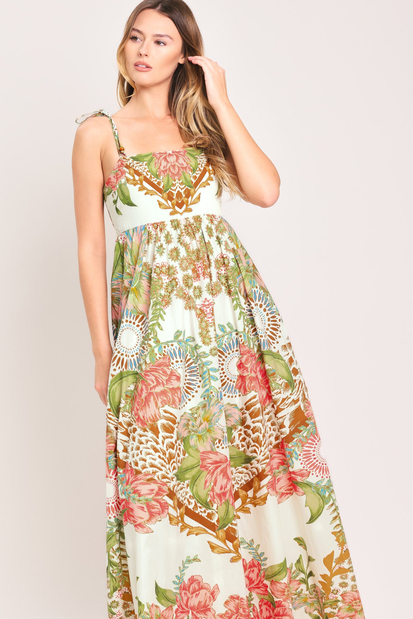 Woman wearing a floral ankle dress featuring straight neckline with shoulder tie, full skirt and smocked back bodice | Flying Tomato