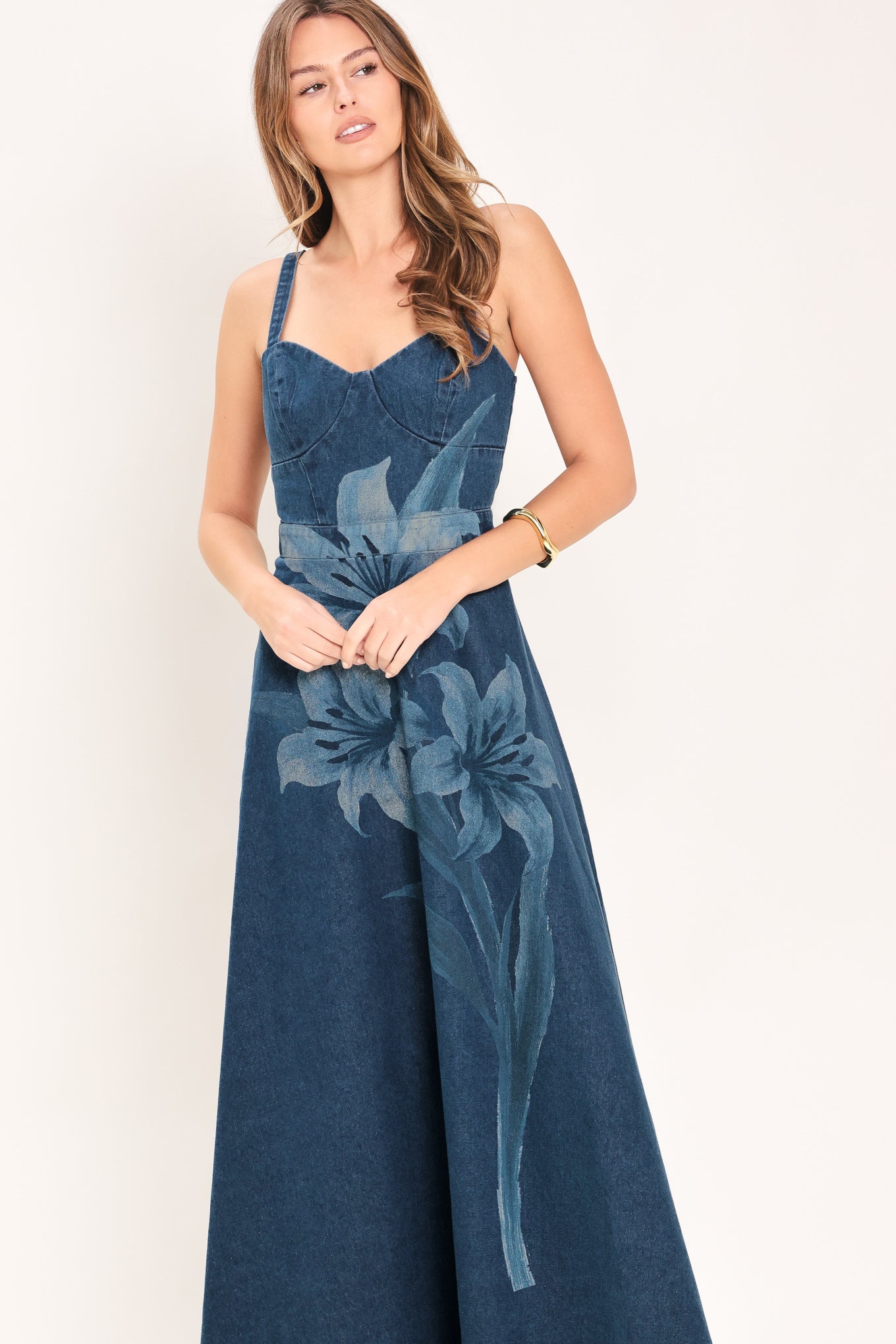 Woman wearing a blue denim midi dress with lilies printed featuring bustier top, straps, circle skirt and back zipper closure | Flying Tomato