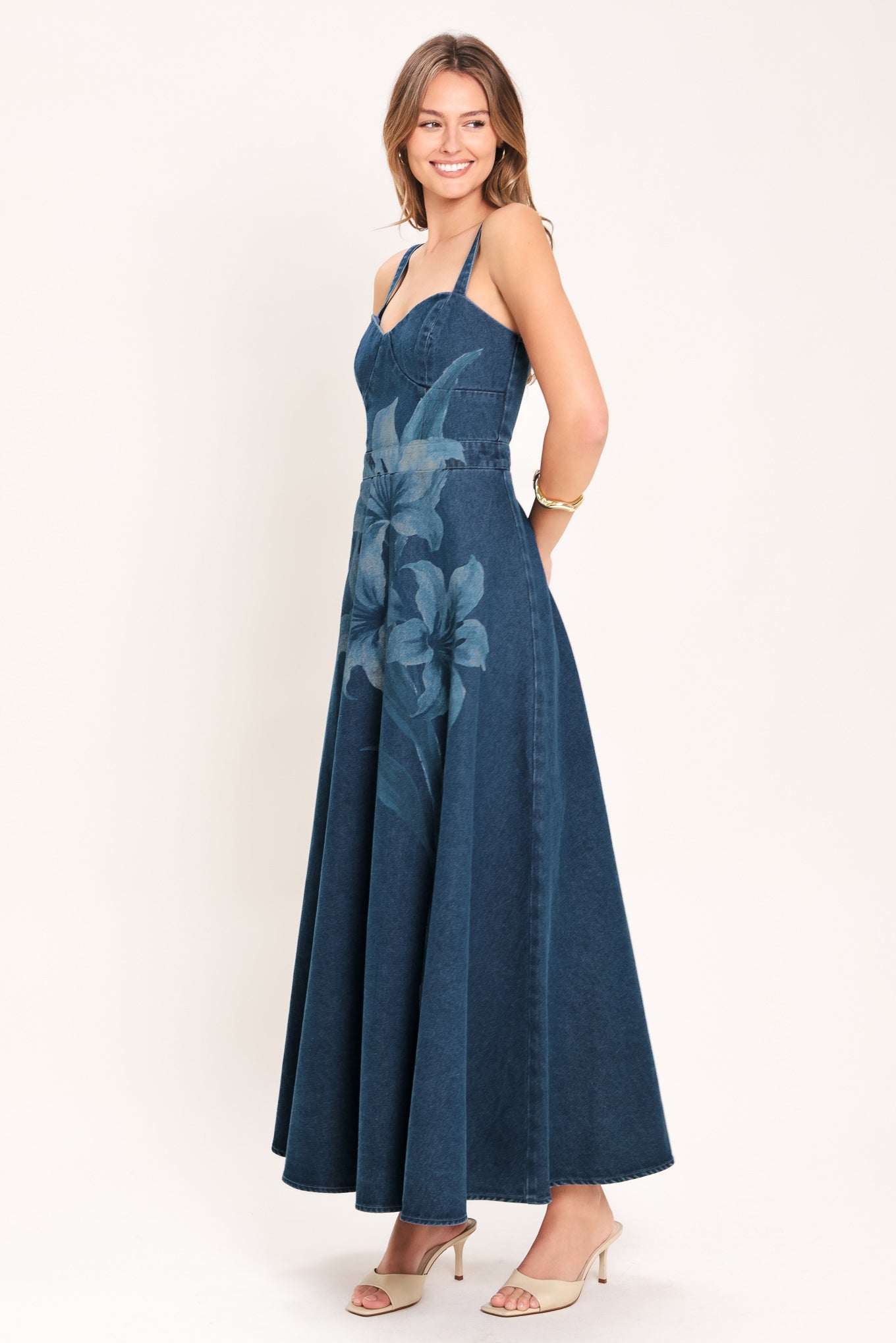 Woman wearing a blue denim midi dress with lilies printed featuring bustier top, straps, circle skirt and back zipper closure | Flying Tomato