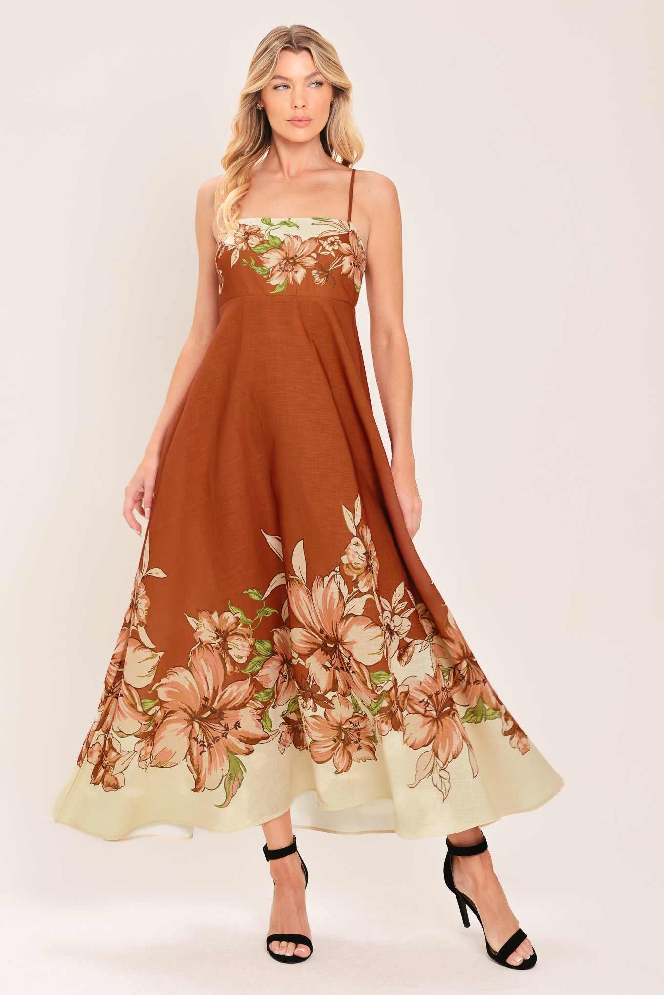 Woman wearing a terracotta midi dress with floral print on the top and bottom, featuring straight neckline, straps, circle skirt and back zipper closure | Flying Tomato