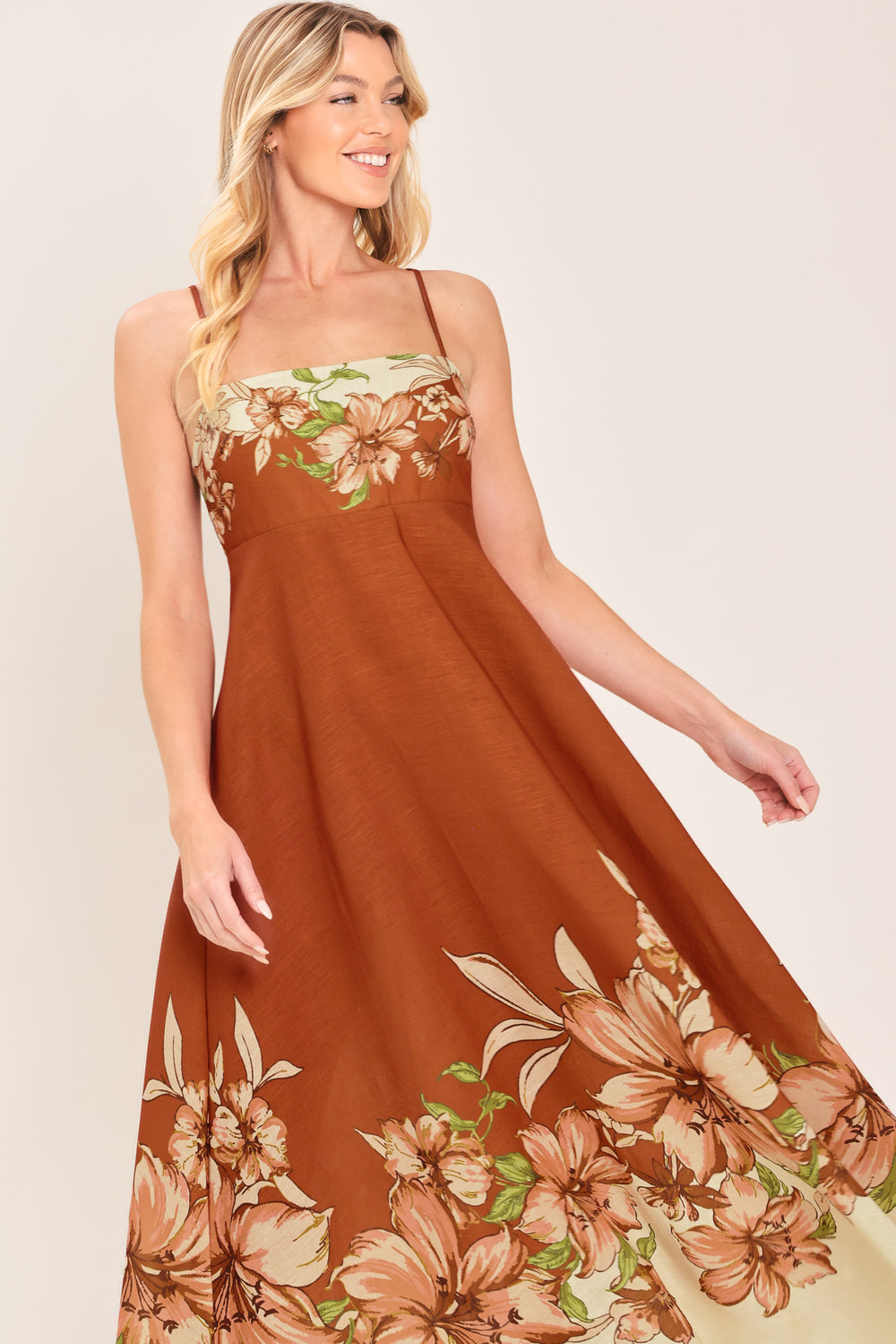 Woman wearing a terracotta midi dress with floral print on the top and bottom, featuring straight neckline, straps, circle skirt and back zipper closure | Flying Tomato