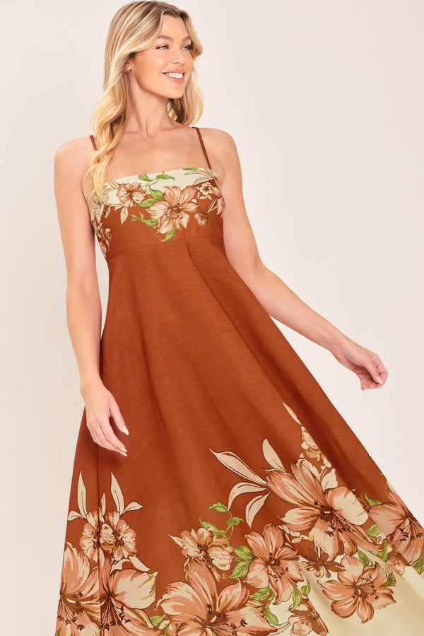 Woman wearing a terracotta midi dress with floral print on the top and bottom, featuring straight neckline, straps, circle skirt and back zipper closure | Flying Tomato