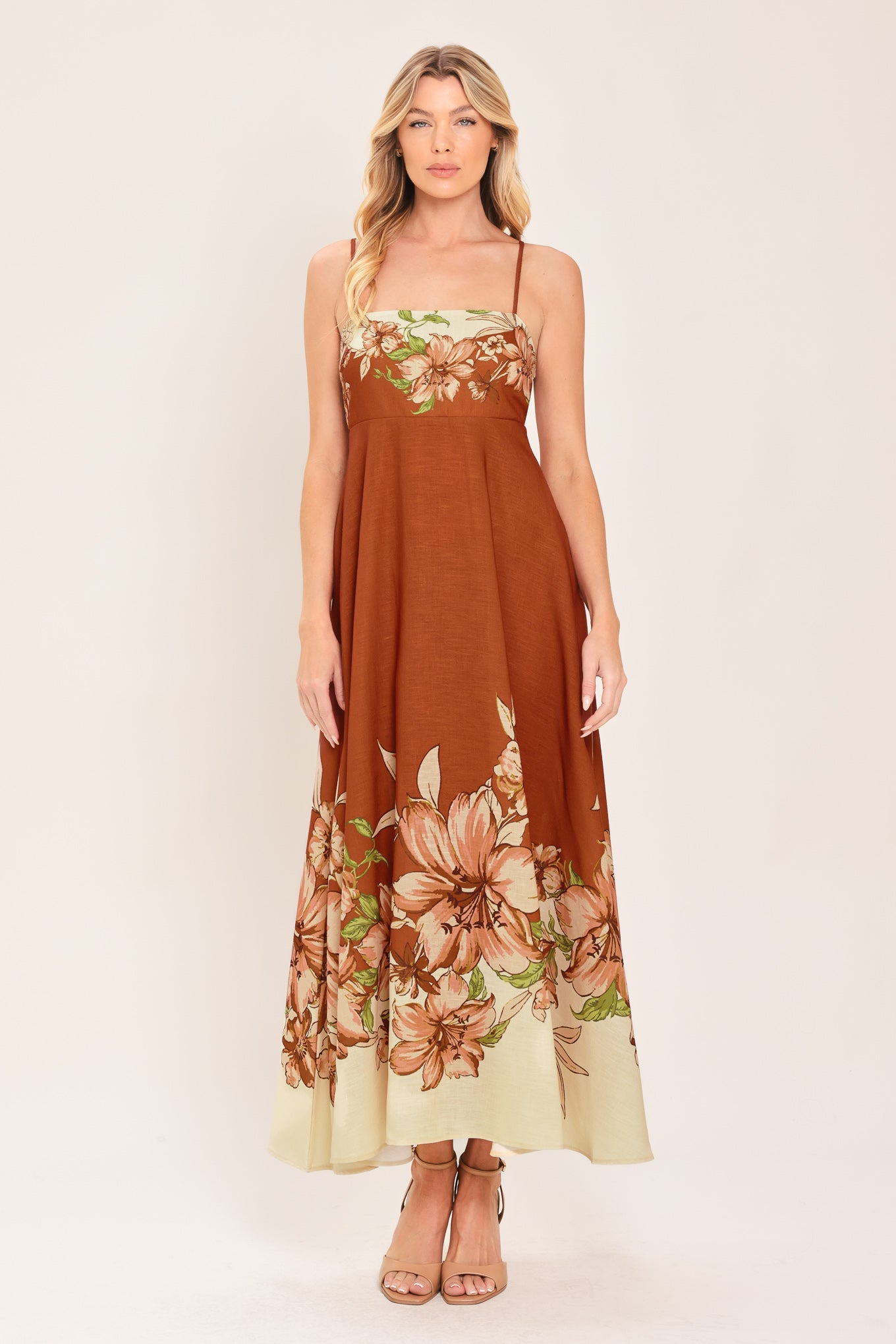 Woman wearing a terracotta midi dress with floral print on the top and bottom, featuring straight neckline, straps, circle skirt and back zipper closure | Flying Tomato