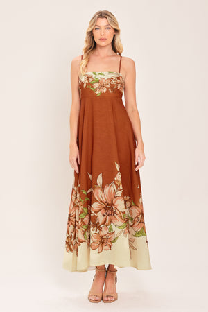 Woman wearing a terracotta midi dress with floral print on the top and bottom, featuring straight neckline, straps, circle skirt and back zipper closure | Flying Tomato