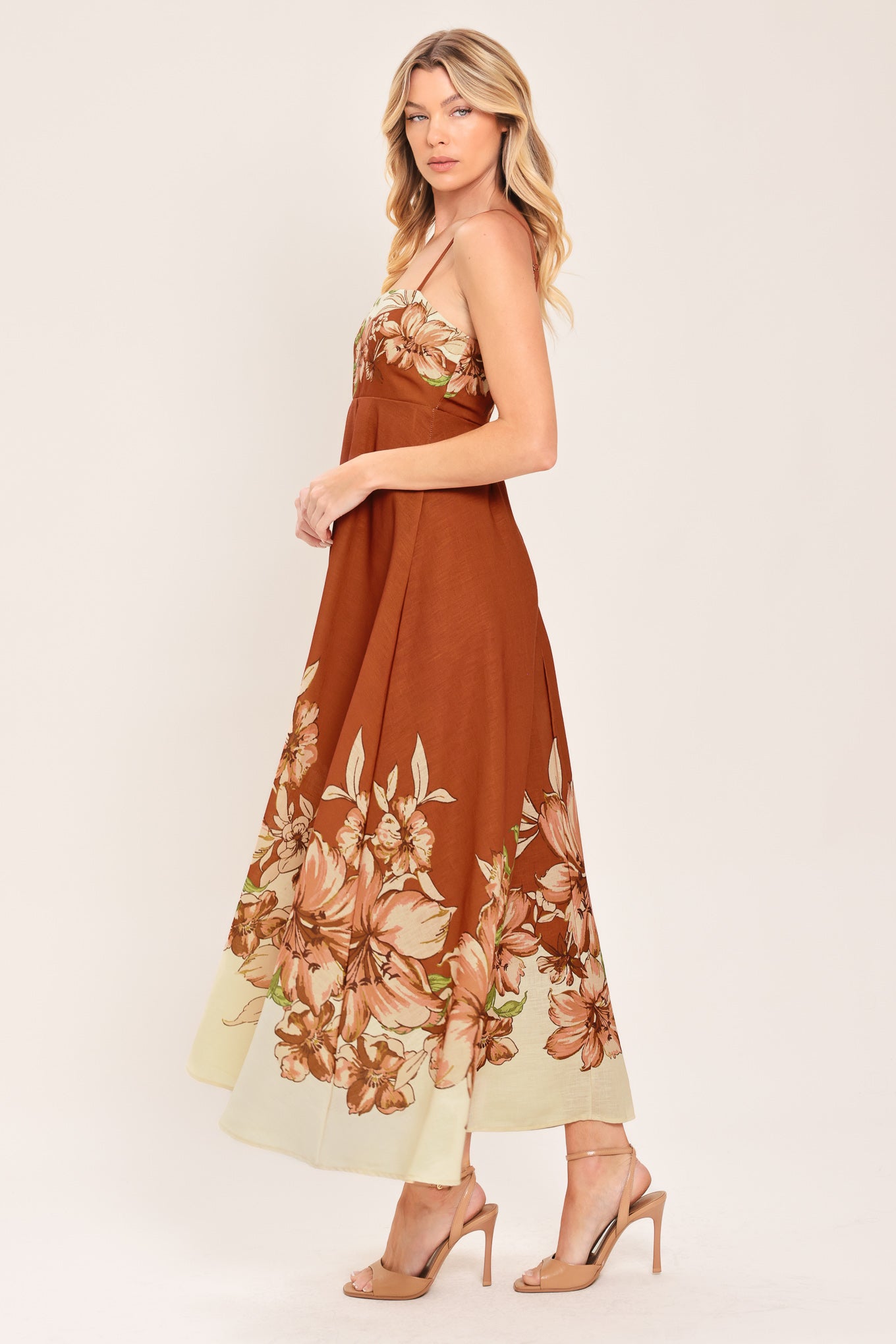 Woman wearing a terracotta midi dress with floral print on the top and bottom, featuring straight neckline, straps, circle skirt and back zipper closure | Flying Tomato