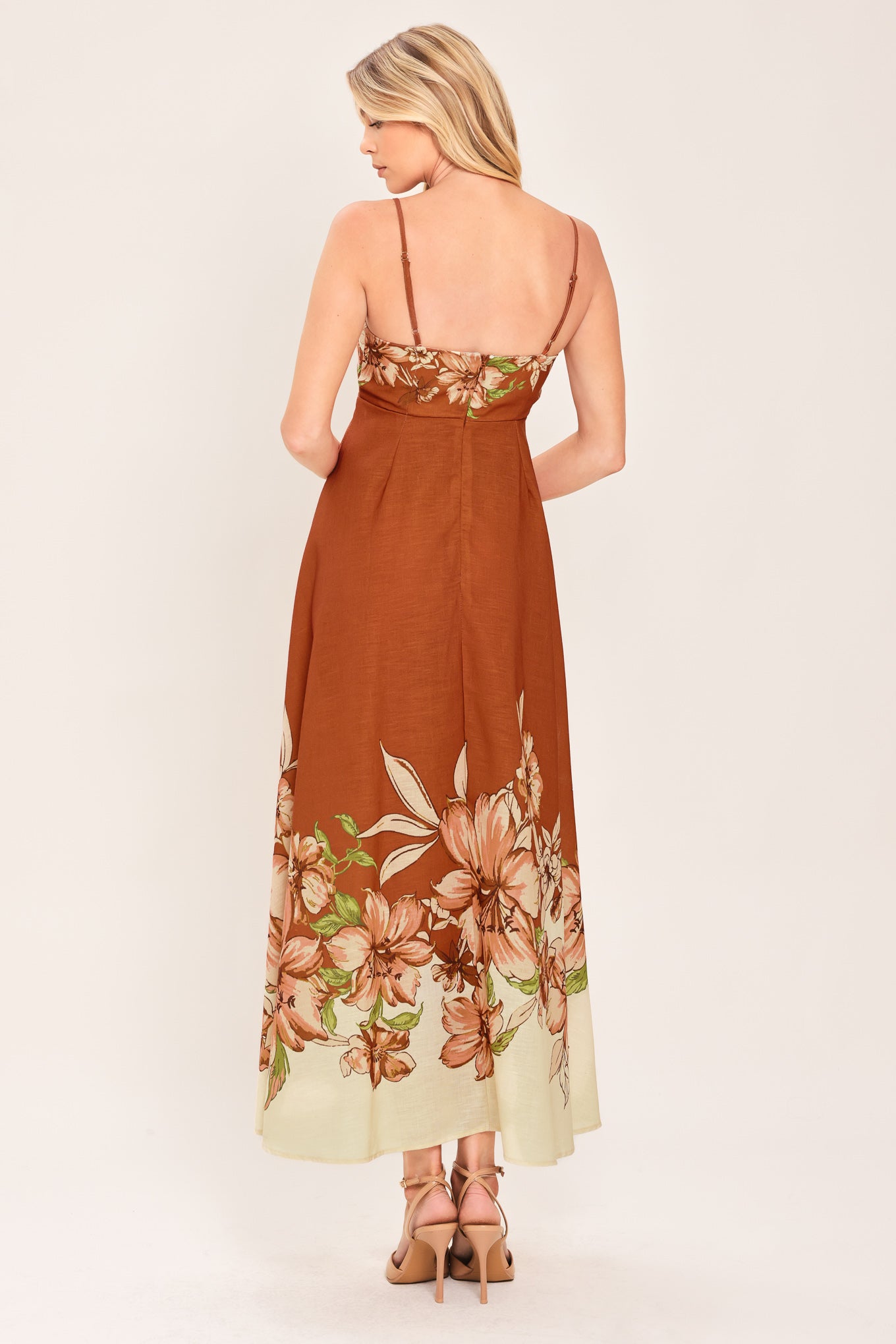Woman wearing a terracotta midi dress with floral print on the top and bottom, featuring straight neckline, straps, circle skirt and back zipper closure | Flying Tomato