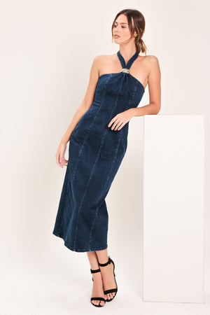 Woman wearing a dark indigo denim midi dress featuring halter neckline with hardware, bare back and zipper closure | Flying Tomato