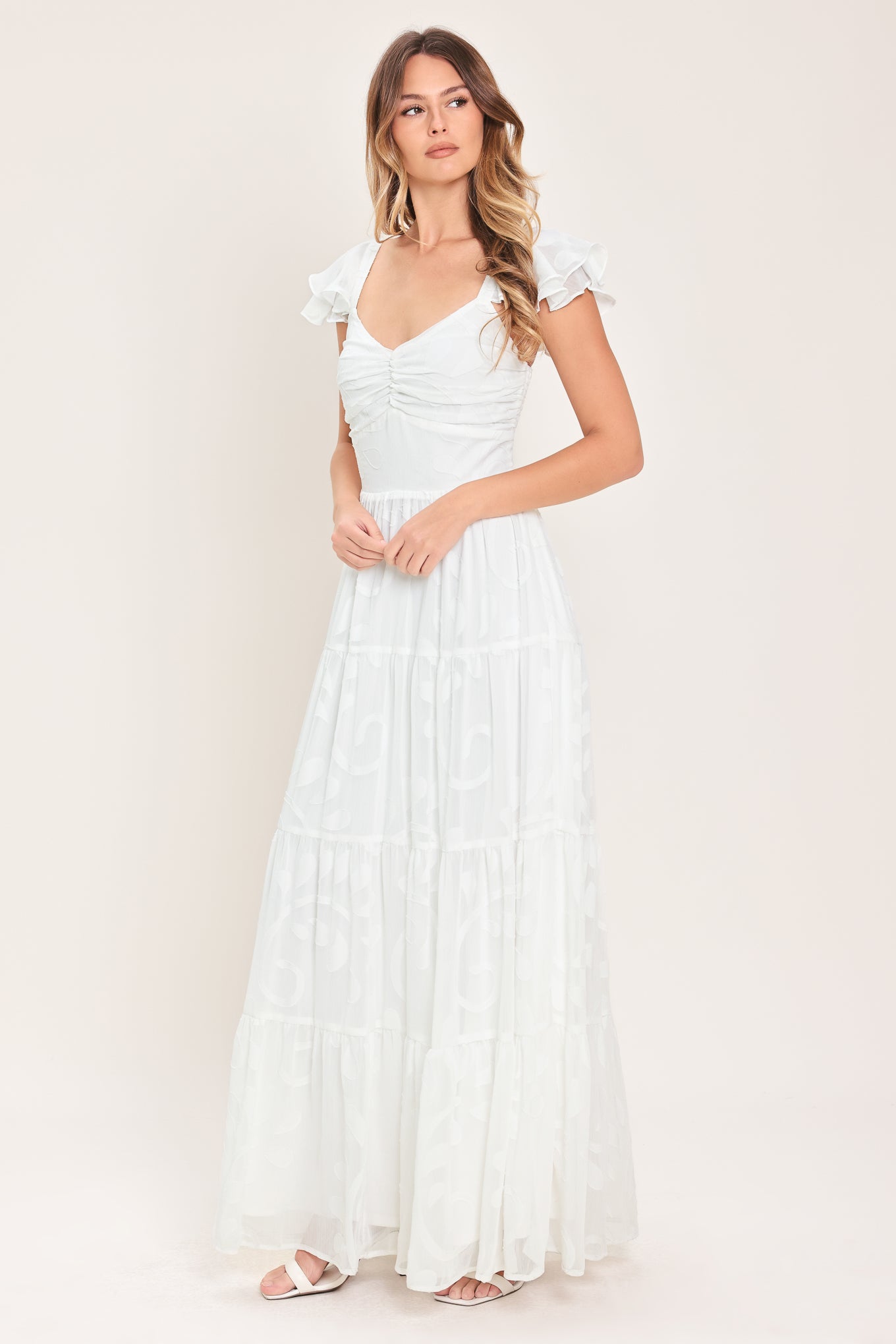 Woman wearing a white maxi dress featuring sweetheart neckline, ruffle sleeve, tier skirt and smocked back bodice  | FREEMARKET