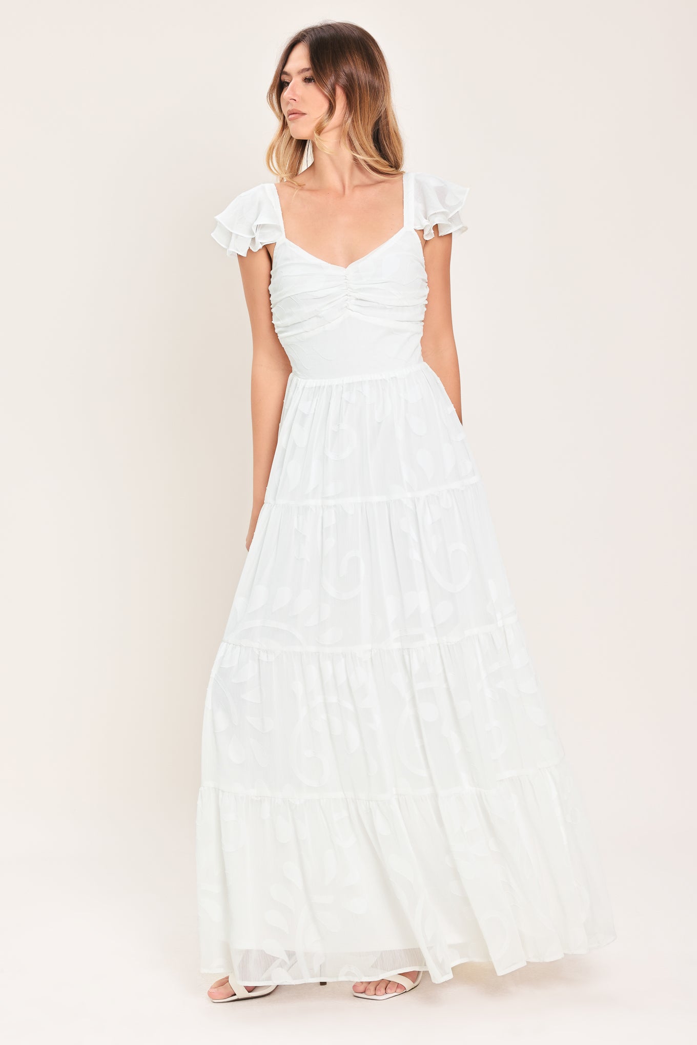 Woman wearing a white maxi dress featuring sweetheart neckline, ruffle sleeve, tier skirt and smocked back bodice  | FREEMARKET