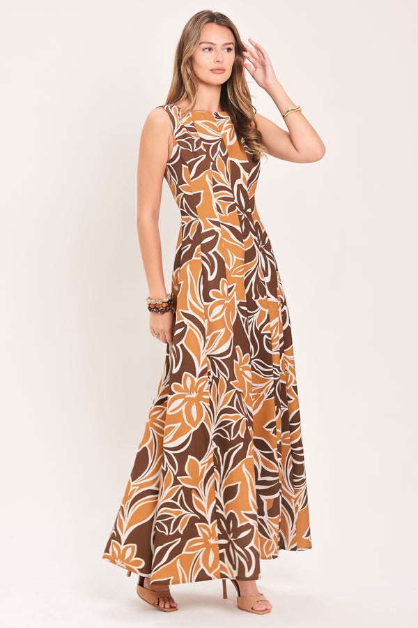 A woman modeling a sleeveless, floor-length maxi dress with a bold brown, tan, and white tropical floral pattern | Flying Tomato