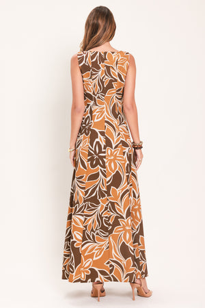 A woman modeling a sleeveless, floor-length maxi dress with a bold brown, tan, and white tropical floral pattern | Flying Tomato
