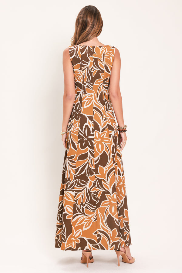 A woman modeling a sleeveless, floor-length maxi dress with a bold brown, tan, and white tropical floral pattern | Flying Tomato