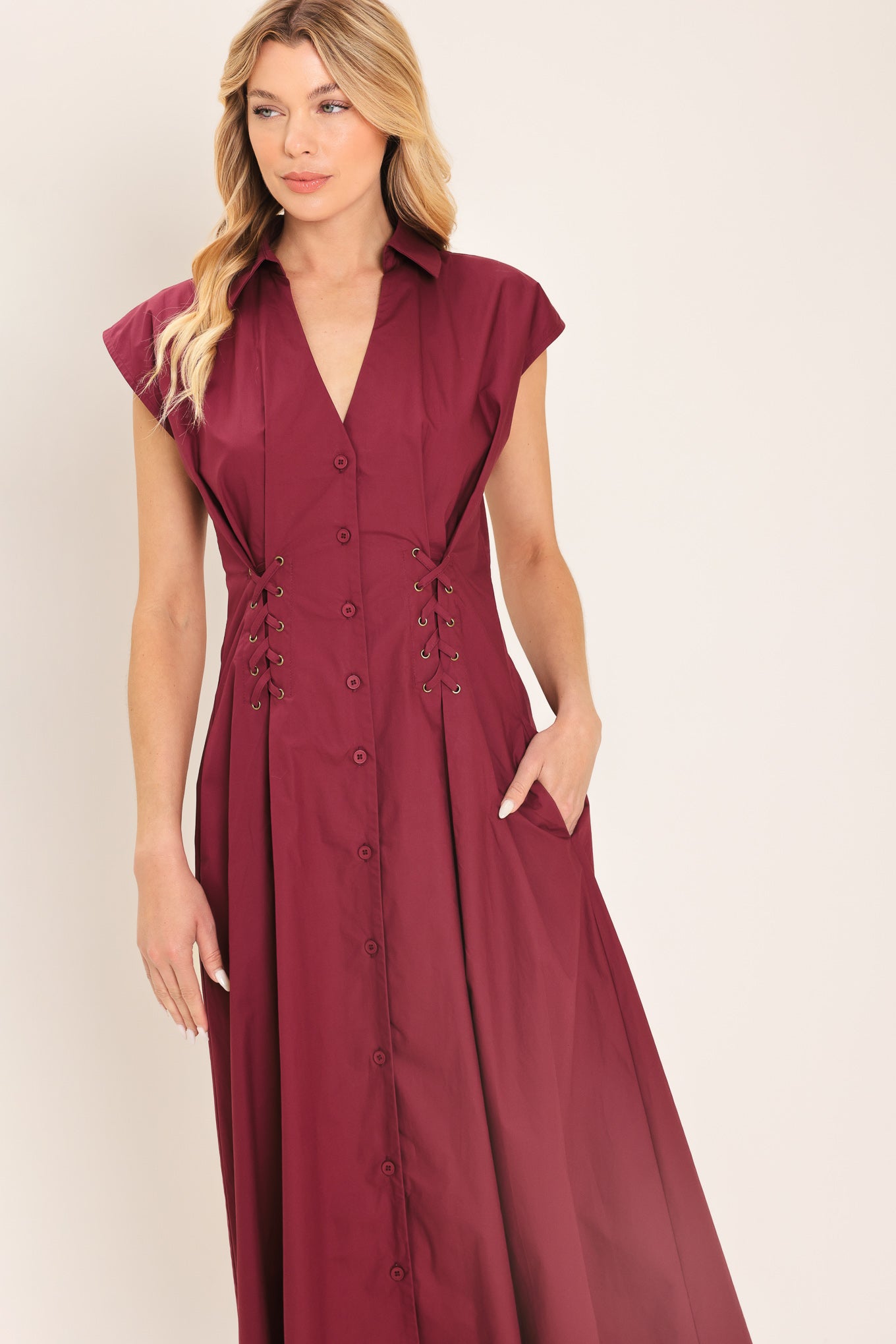 Woman wearing a burgundy midi dress featuring V neckline with collared finish, short sleeve, lace up corset waist and front button down | Flying Tomato
