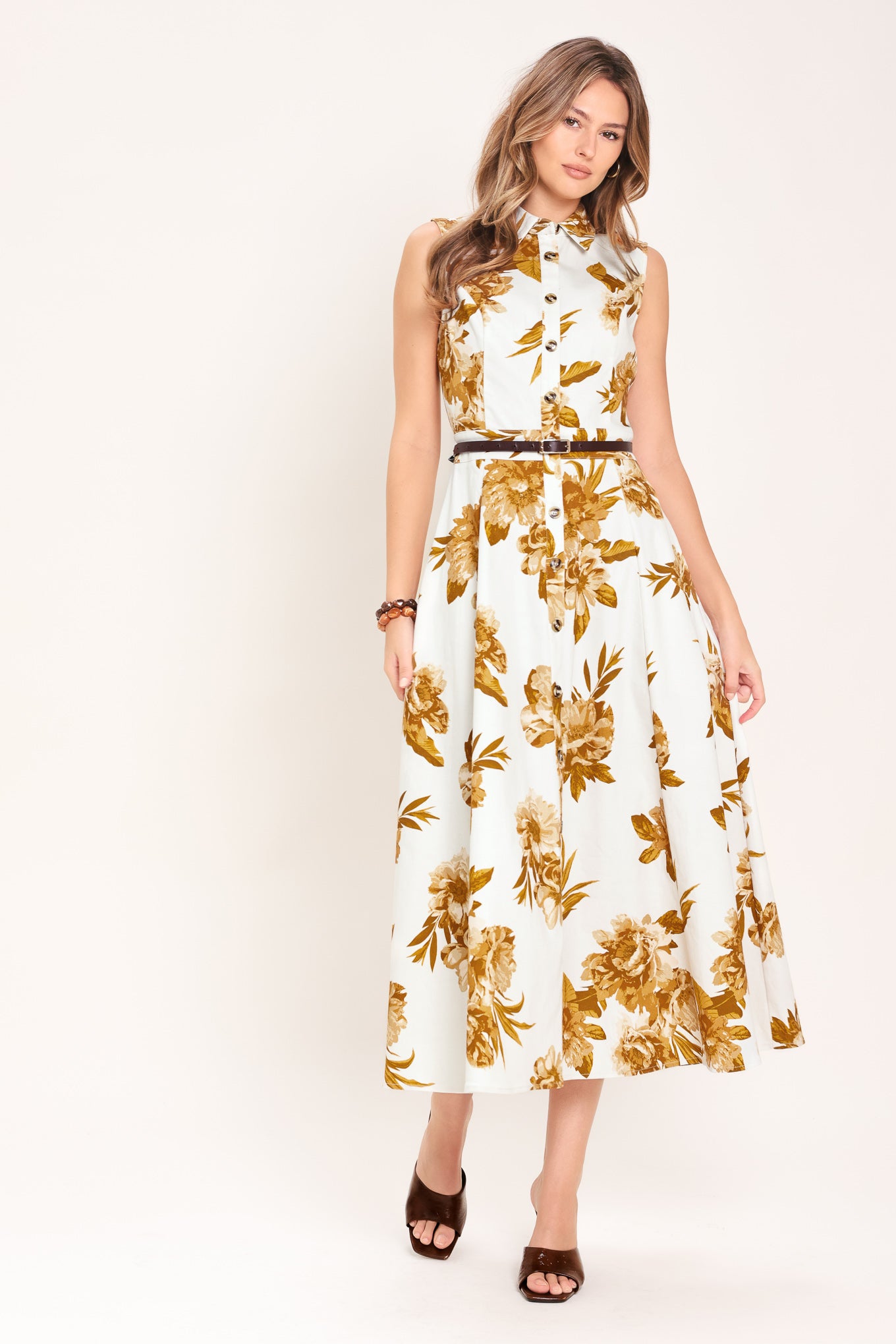 Woman wearing a sleeveless ivory midi dress with brown floral print featuring collar, front button down, contrasting belt and circle skirt | Flying Tomato
