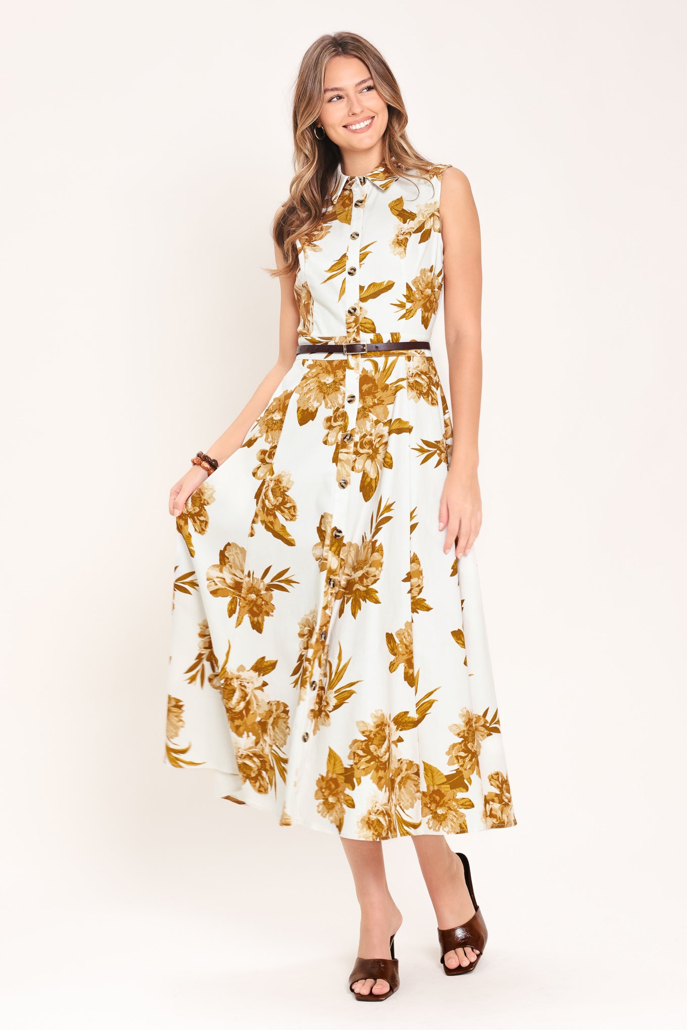Woman wearing a sleeveless ivory midi dress with brown floral print featuring collar, front button down, contrasting belt and circle skirt | Flying Tomato