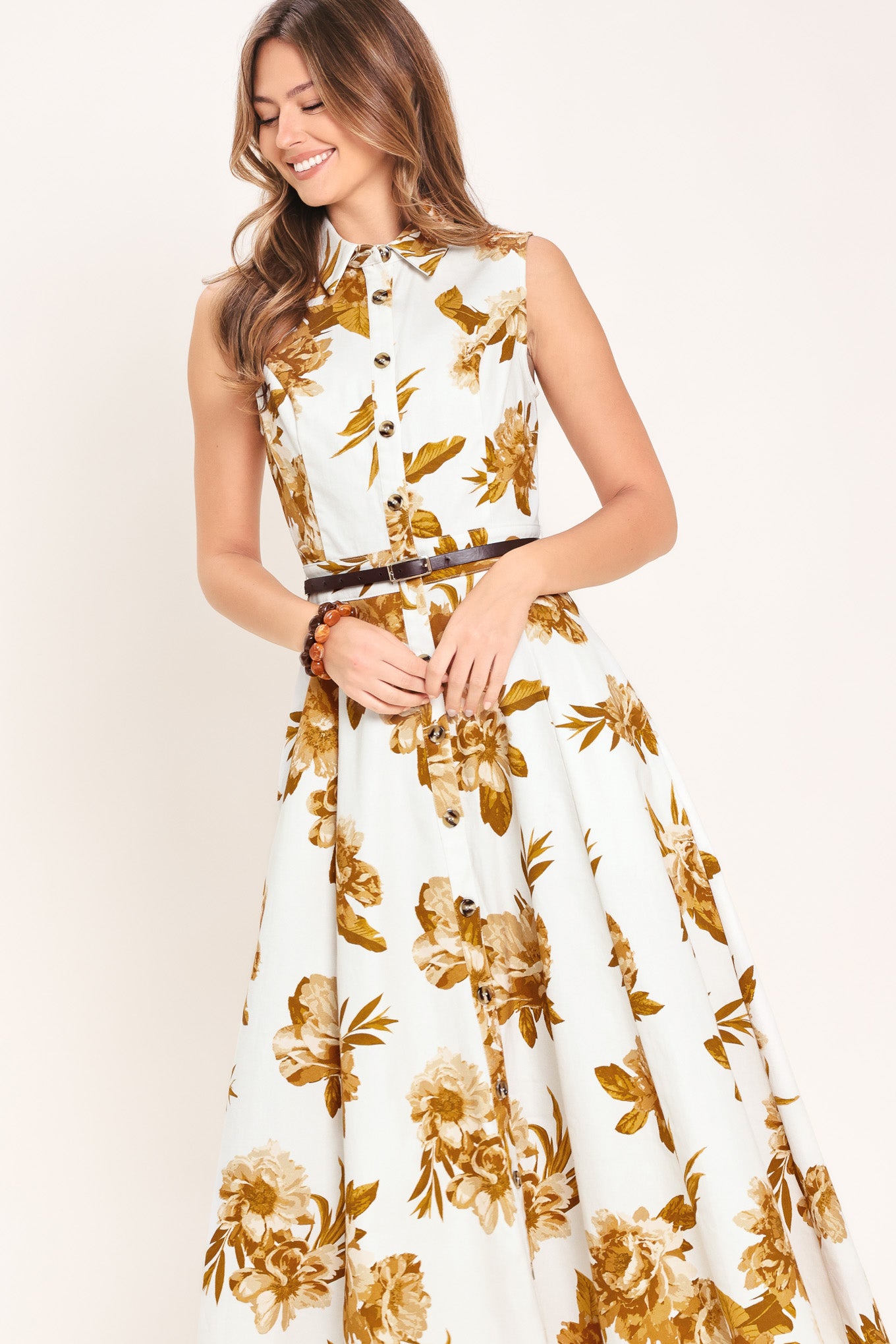 Woman wearing a sleeveless ivory midi dress with brown floral print featuring collar, front button down, contrasting belt and circle skirt | Flying Tomato