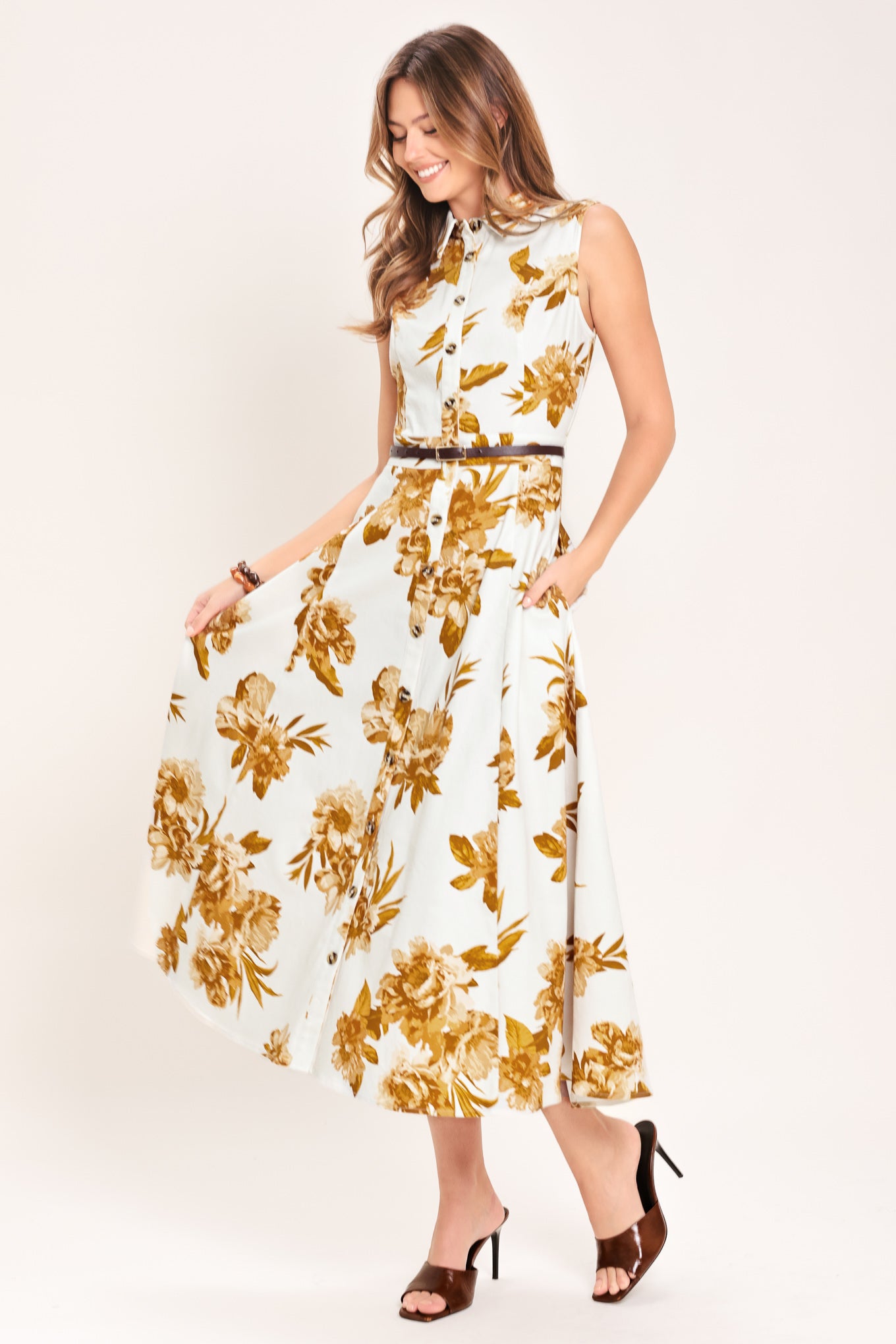 Woman wearing a sleeveless ivory midi dress with brown floral print featuring collar, front button down, contrasting belt and circle skirt | Flying Tomato