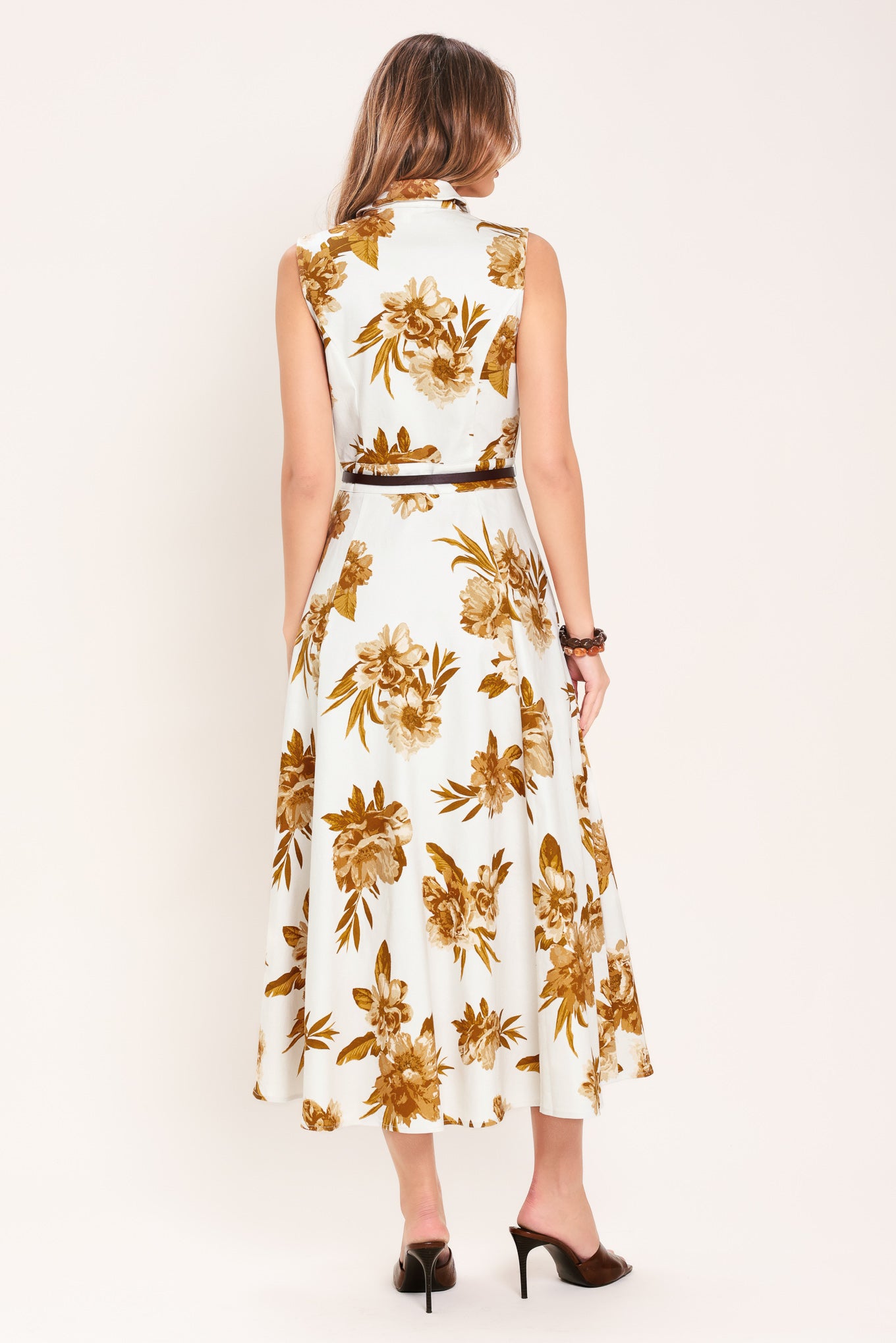 Woman wearing a sleeveless ivory midi dress with brown floral print featuring collar, front button down, contrasting belt and circle skirt | Flying Tomato