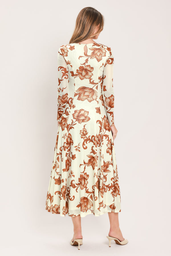 A woman wearing a long-sleeve midi dress with a cream base and a brown baroque-style floral pattern | Flying Tomato
