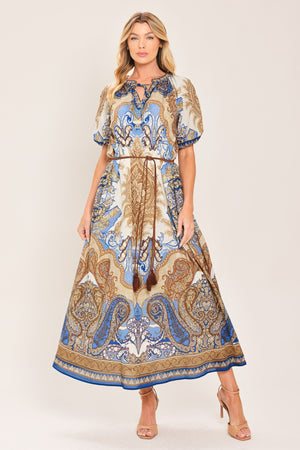 Woman wearing a navy blue pattered  printed woven midi dress featuring round neckline with ruffle edge and tie, short puff sleeve and contrasting belt with tassel | Flying Tomato