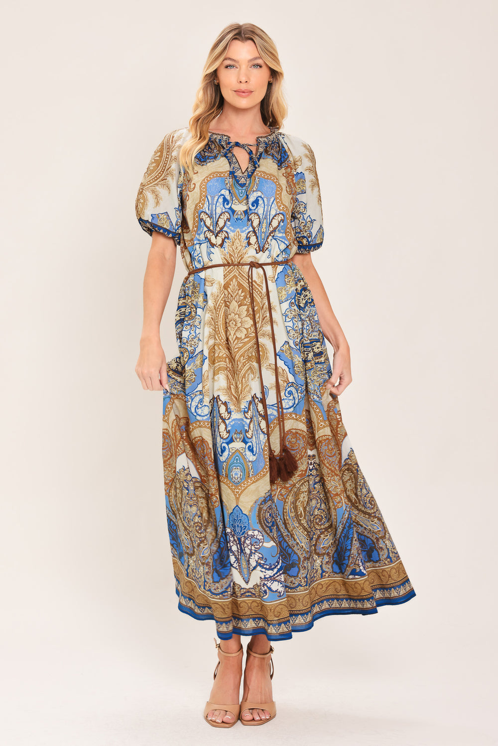 Woman wearing a navy blue pattered  printed woven midi dress featuring round neckline with ruffle edge and tie, short puff sleeve and contrasting belt with tassel | Flying Tomato