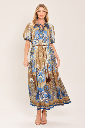 Woman wearing a navy blue pattered  printed woven midi dress featuring round neckline with ruffle edge and tie, short puff sleeve and contrasting belt with tassel | Flying Tomato