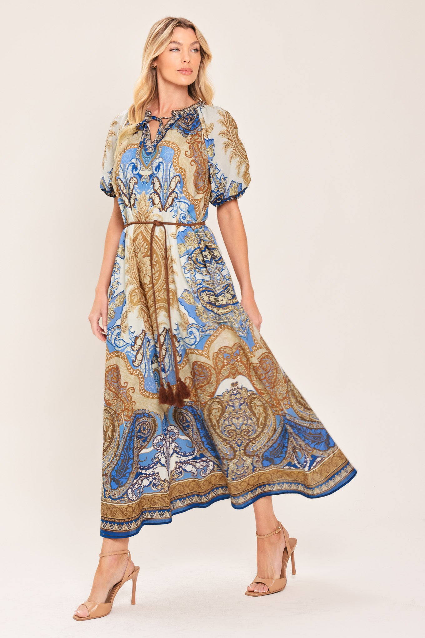 Woman wearing a navy blue pattered  printed woven midi dress featuring round neckline with ruffle edge and tie, short puff sleeve and contrasting belt with tassel | Flying Tomato