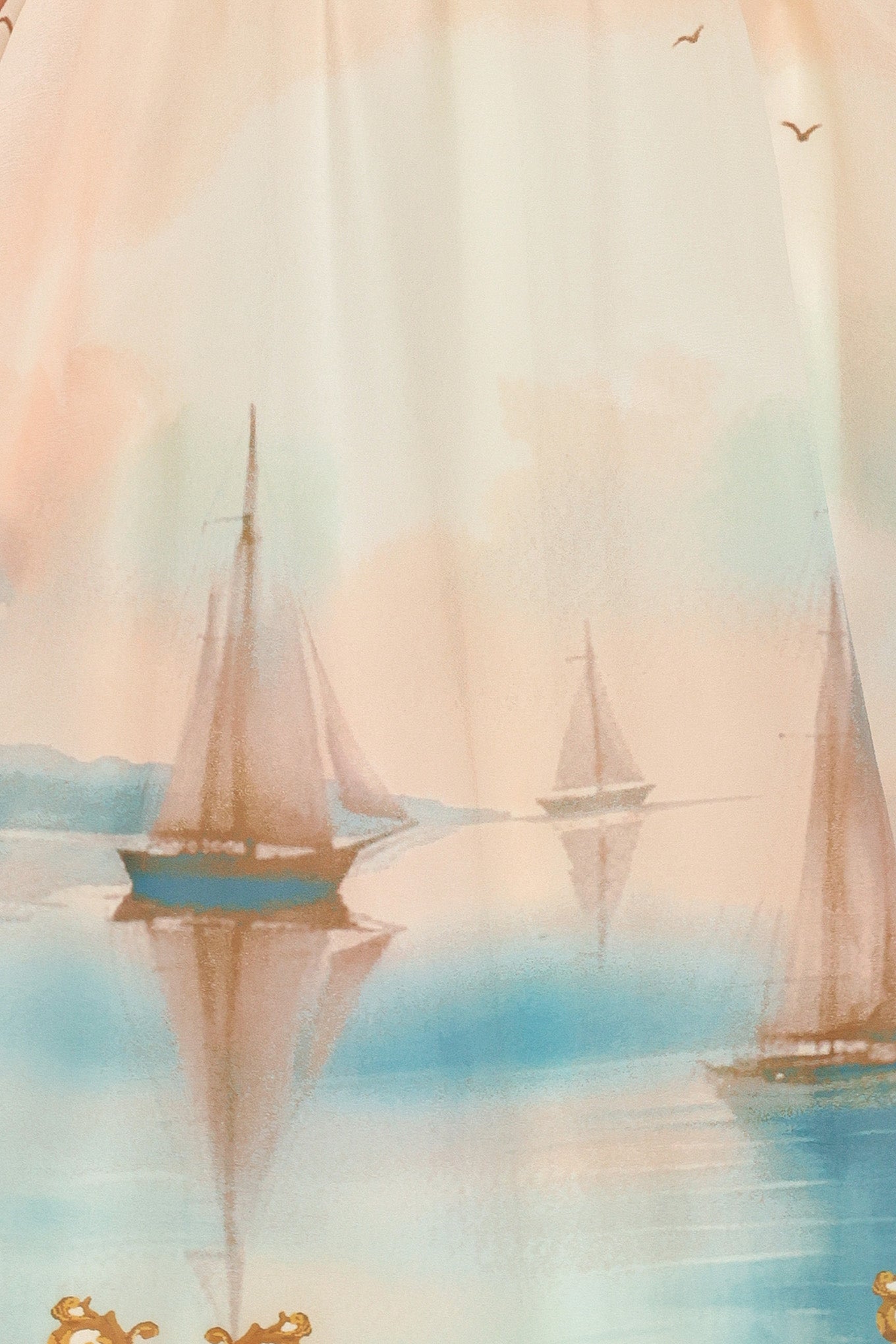 Close up of long, elegant dress with sail boats and gold details featuring a straight neckline, shoulder tie, full skirt and smocked back bodice | Flying Tomato
