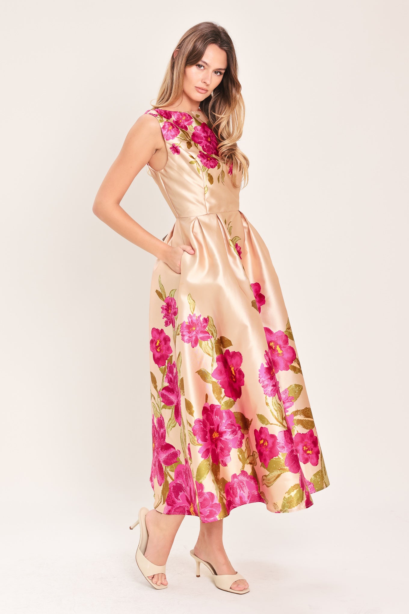 Woman wearing a sleeveless pink floral midi dress featuring wide neckline, full skirt, back cut out and zipper closure | Flying Tomato