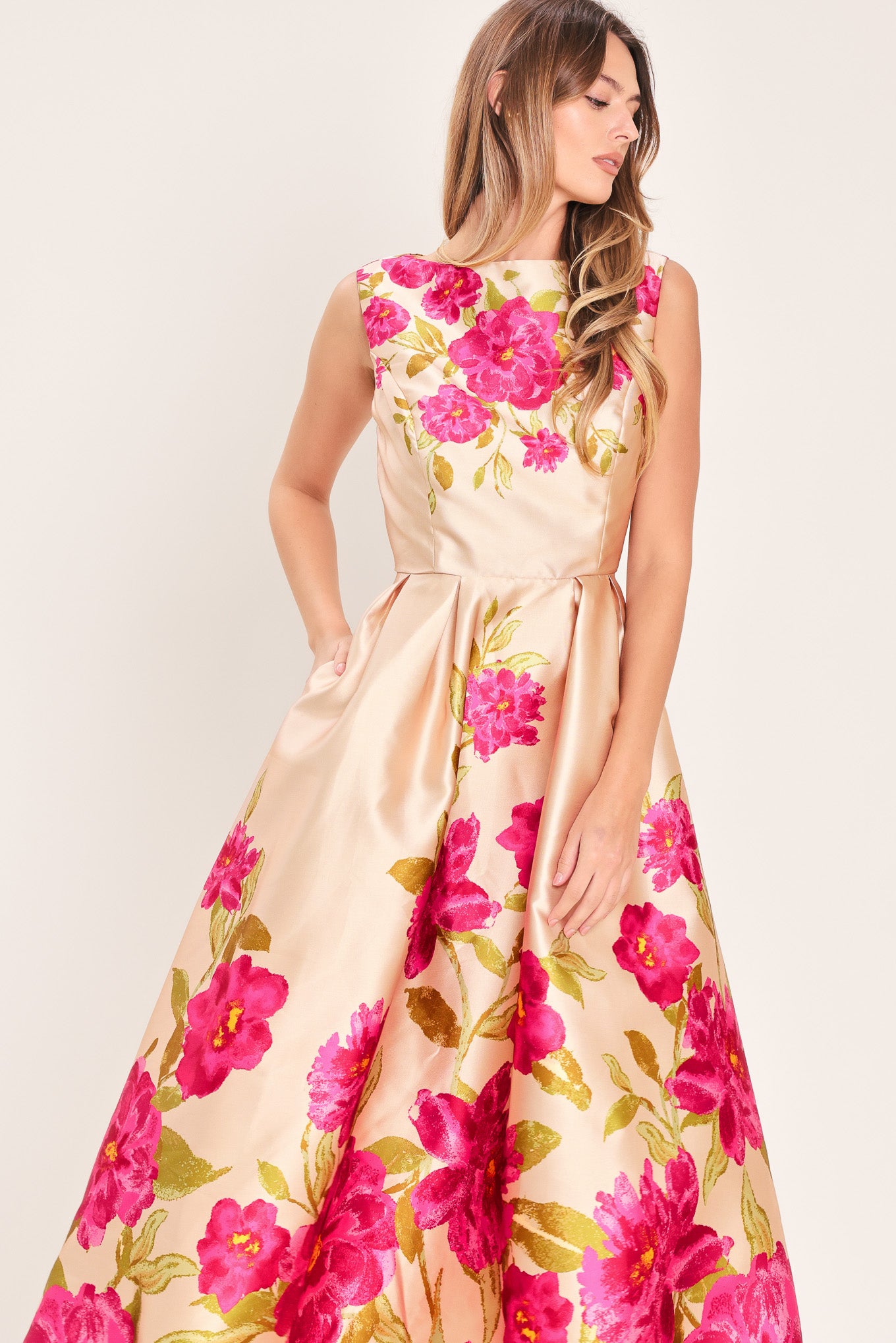 Woman wearing a sleeveless pink floral midi dress featuring wide neckline, full skirt, back cut out and zipper closure | Flying Tomato