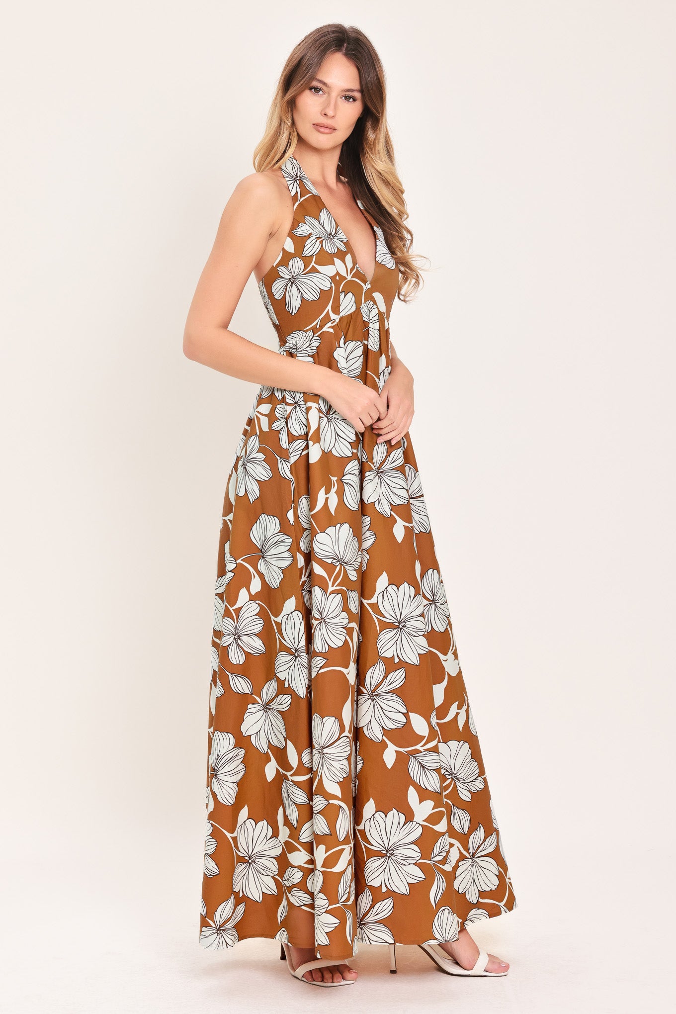 Woman wearing a camel and white with black lineart floral maxi dress maxi dress featuring halter neckline with back neck tie, bare back and smocked bodice | Flying Tomato