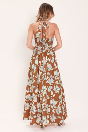 Woman wearing a camel and white with black lineart floral maxi dress maxi dress featuring halter neckline with back neck tie, bare back and smocked bodice | Flying Tomato