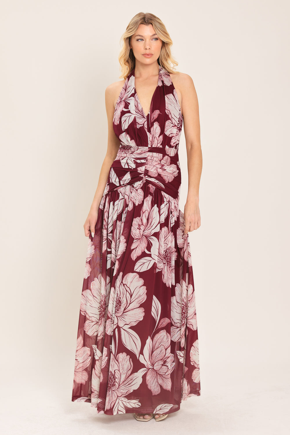 Woman wearing a burgundy floral power mesh maxi dress featuring V halter neckline, shirred mid- drift, bare back and zipper closure | Flying Tomato