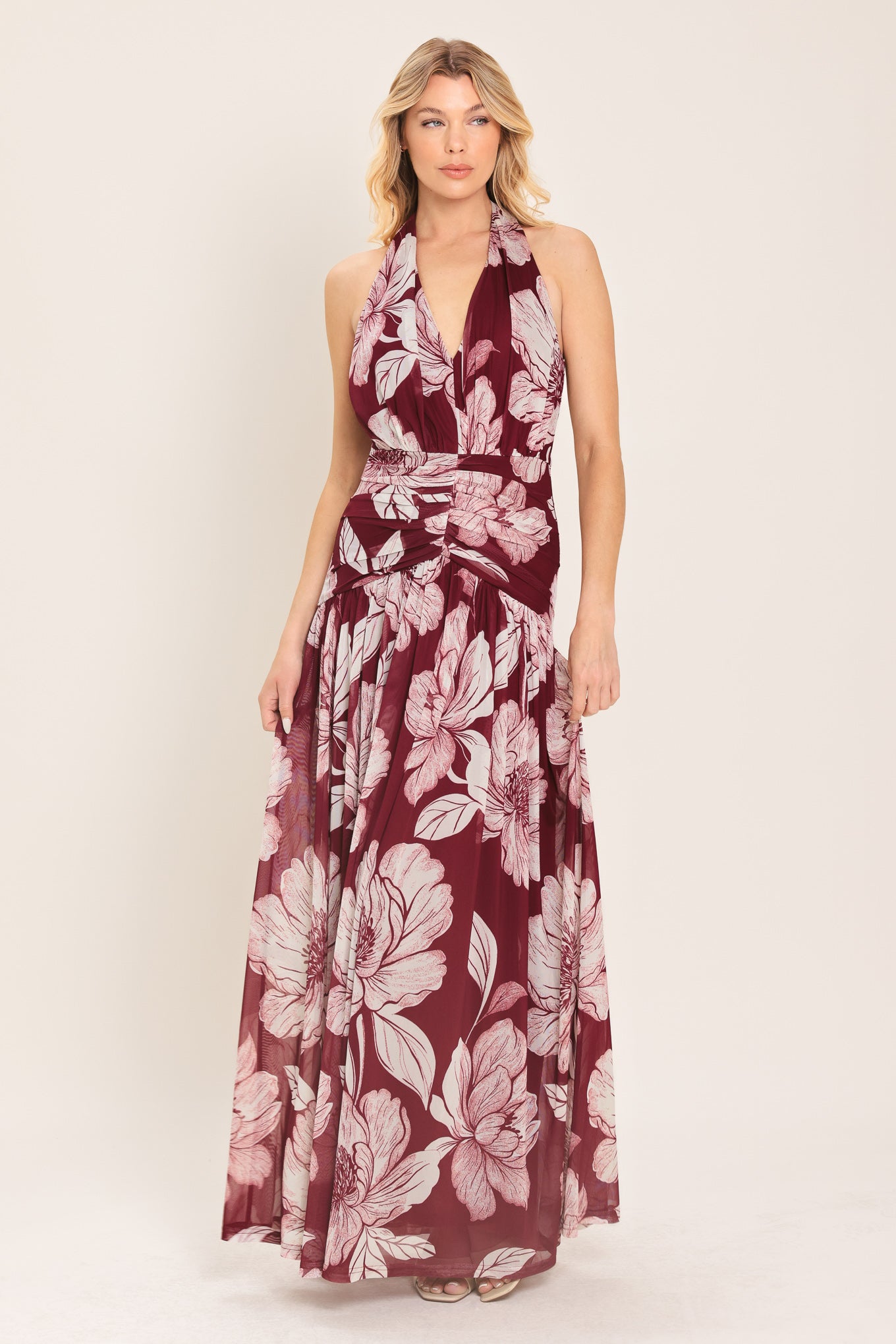 Woman wearing a burgundy floral power mesh maxi dress featuring V halter neckline, shirred mid- drift, bare back and zipper closure | Flying Tomato