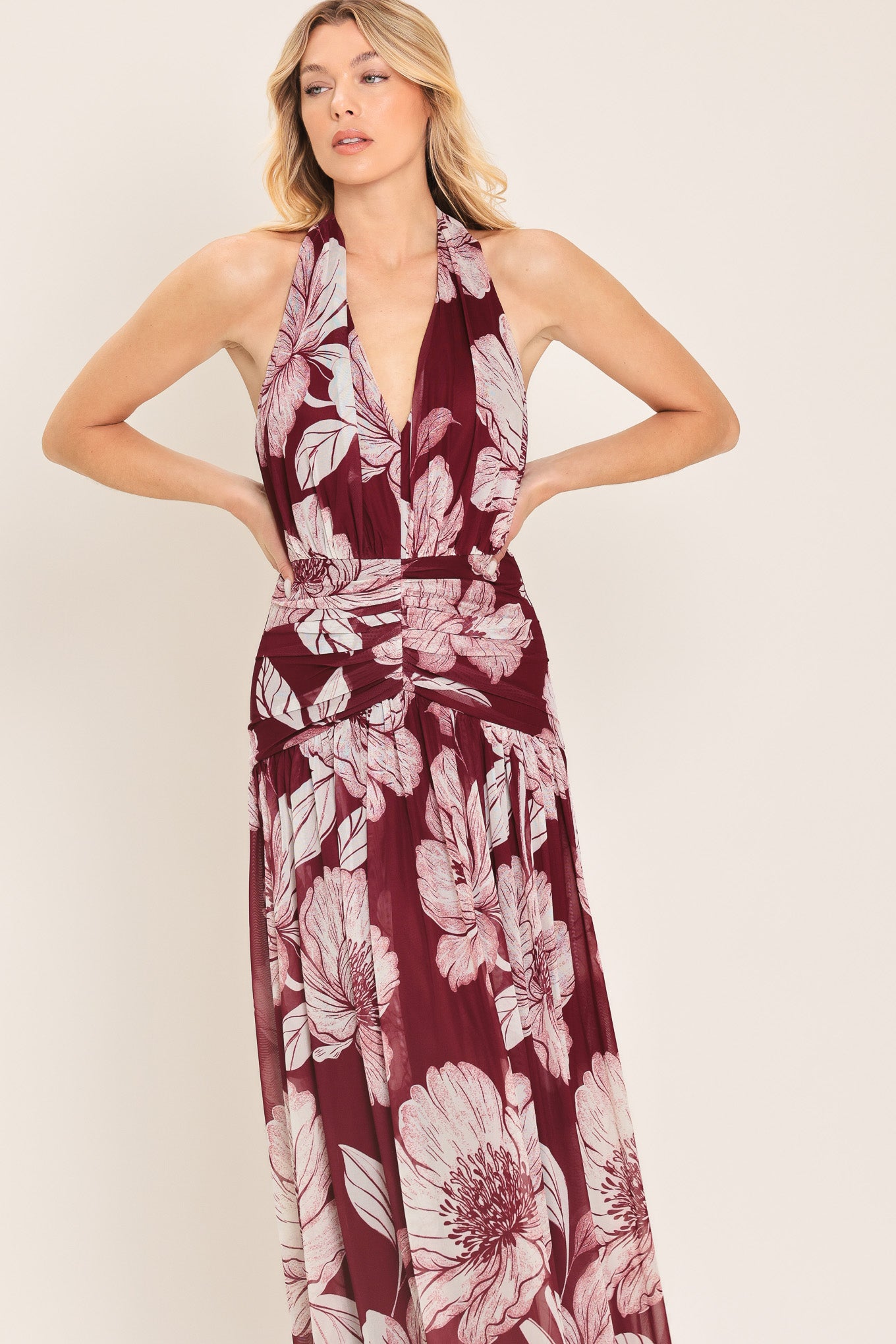 Woman wearing a burgundy floral power mesh maxi dress featuring V halter neckline, shirred mid- drift, bare back and zipper closure | Flying Tomato