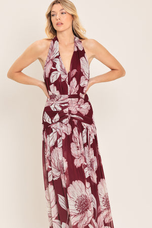 Woman wearing a burgundy floral power mesh maxi dress featuring V halter neckline, shirred mid- drift, bare back and zipper closure | Flying Tomato