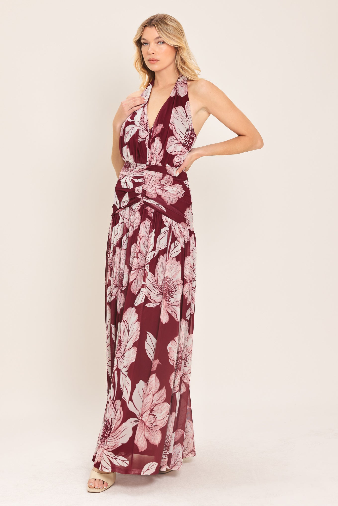 Woman wearing a burgundy floral power mesh maxi dress featuring V halter neckline, shirred mid- drift, bare back and zipper closure | Flying Tomato