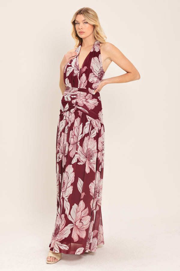 Woman wearing a burgundy floral power mesh maxi dress featuring V halter neckline, shirred mid- drift, bare back and zipper closure | Flying Tomato