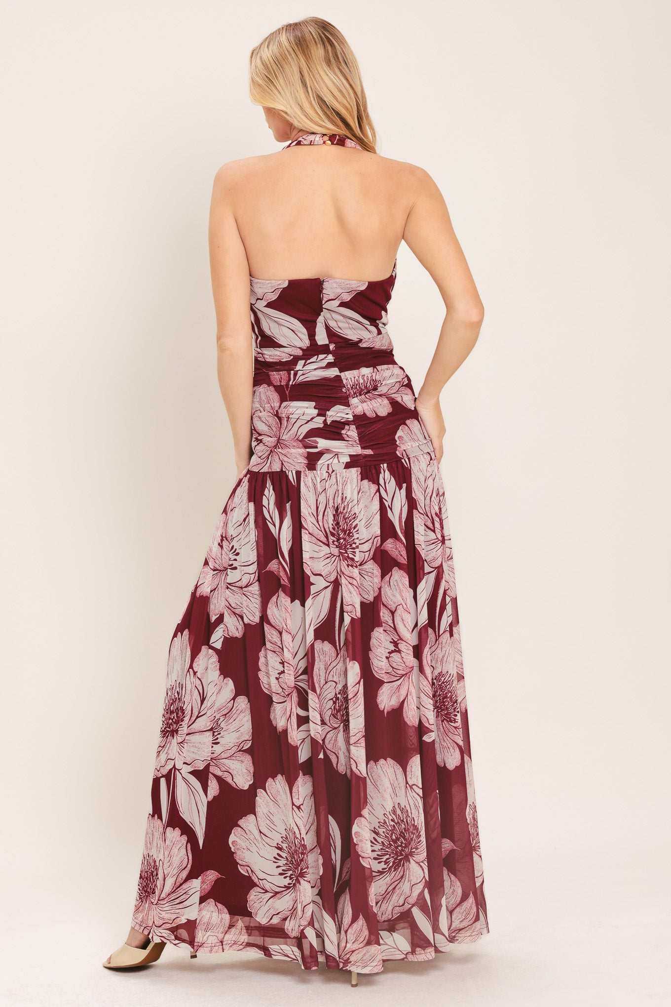 Woman wearing a burgundy floral power mesh maxi dress featuring V halter neckline, shirred mid- drift, bare back and zipper closure | Flying Tomato