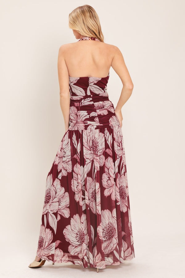 Woman wearing a burgundy floral power mesh maxi dress featuring V halter neckline, shirred mid- drift, bare back and zipper closure | Flying Tomato