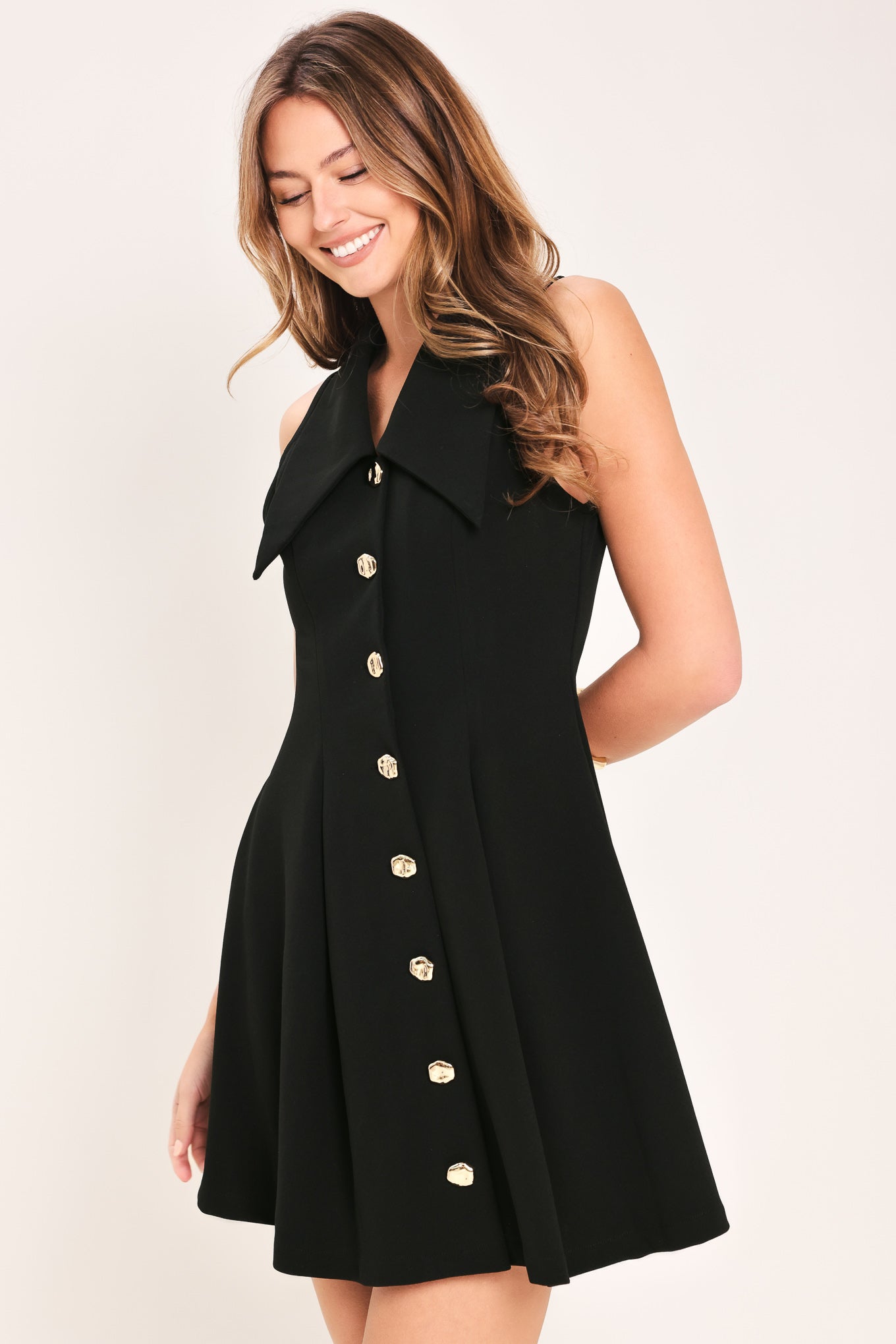 Woman wearing a black sleeveless  woven mini dress featuring peter pan collar, button down and circle skirt | Flying Tomato