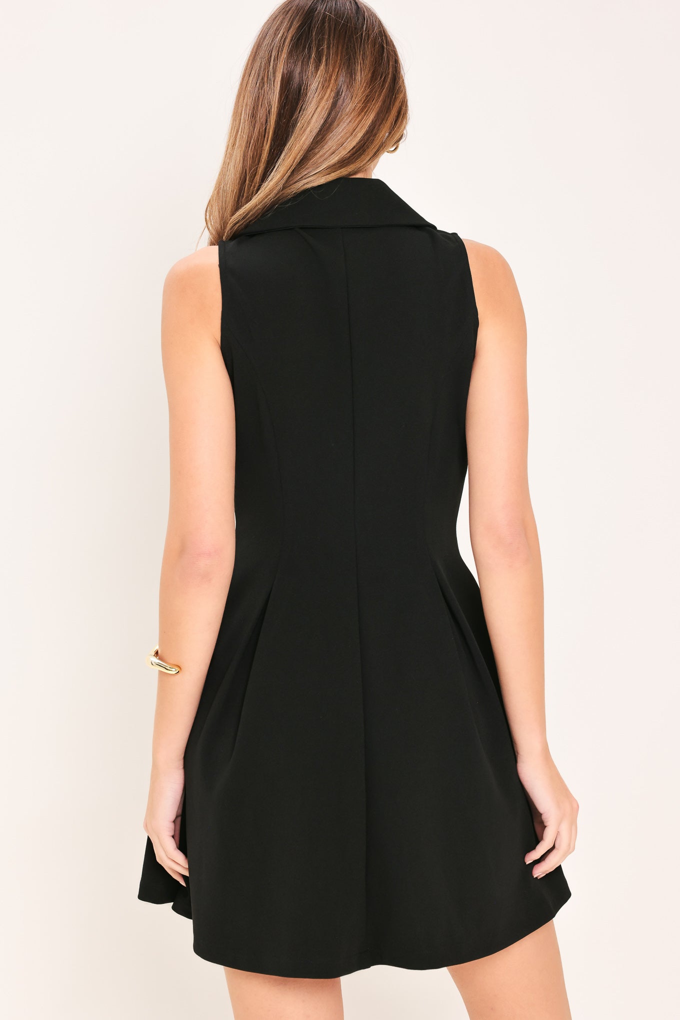 Woman wearing a black sleeveless  woven mini dress featuring peter pan collar, button down and circle skirt | Flying Tomato